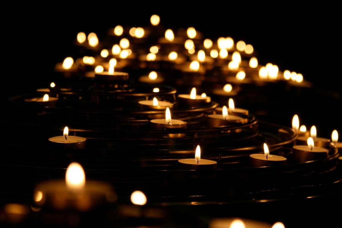 Image of votive candles burning in a darkened space, photo by Mike Labrum